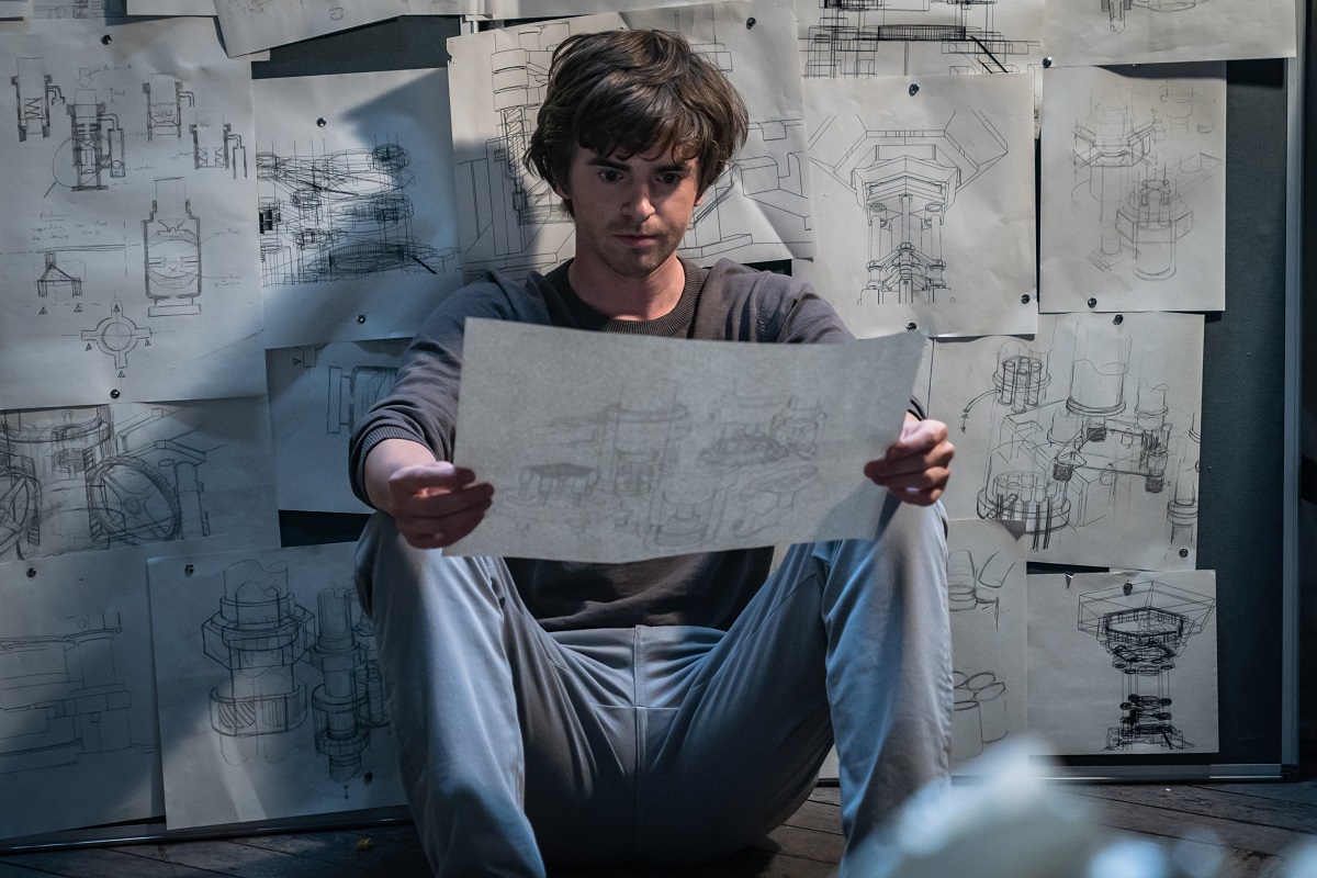 Freddie Highmore examining blueprints in a still from