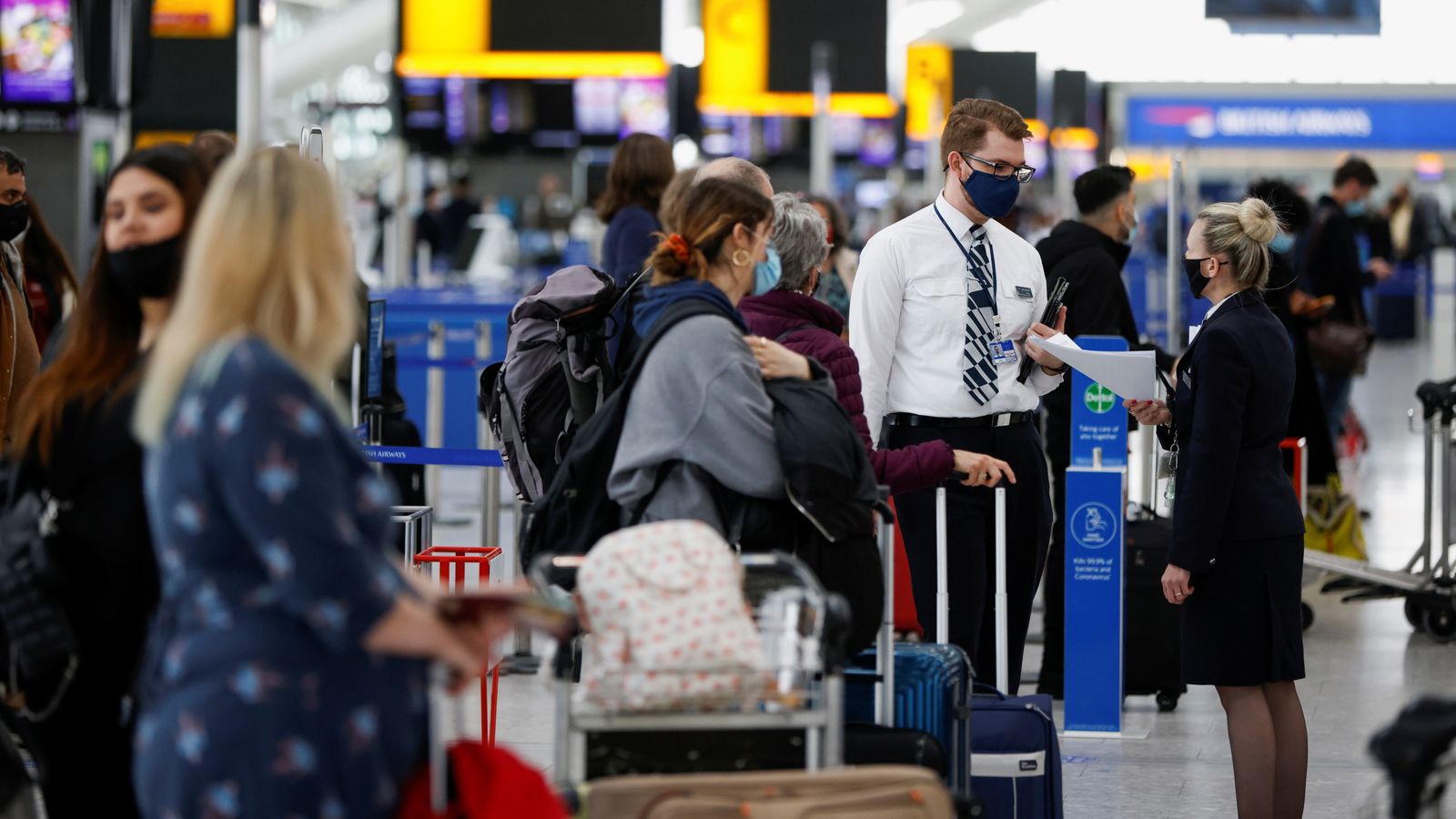 Passengers queue for check-in desks in the departures area of Terminal 5 at Heathrow Airport in London