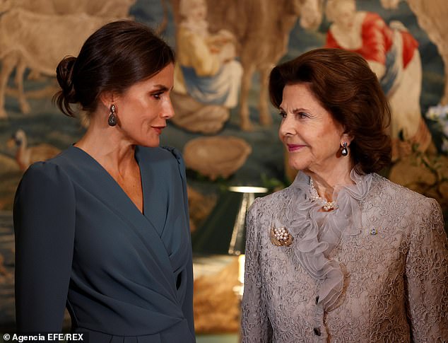 La reina Silvia (en la foto a la derecha, con Leticia) lució un vestido gris con detalles de encaje, para complementar su look con perlas.