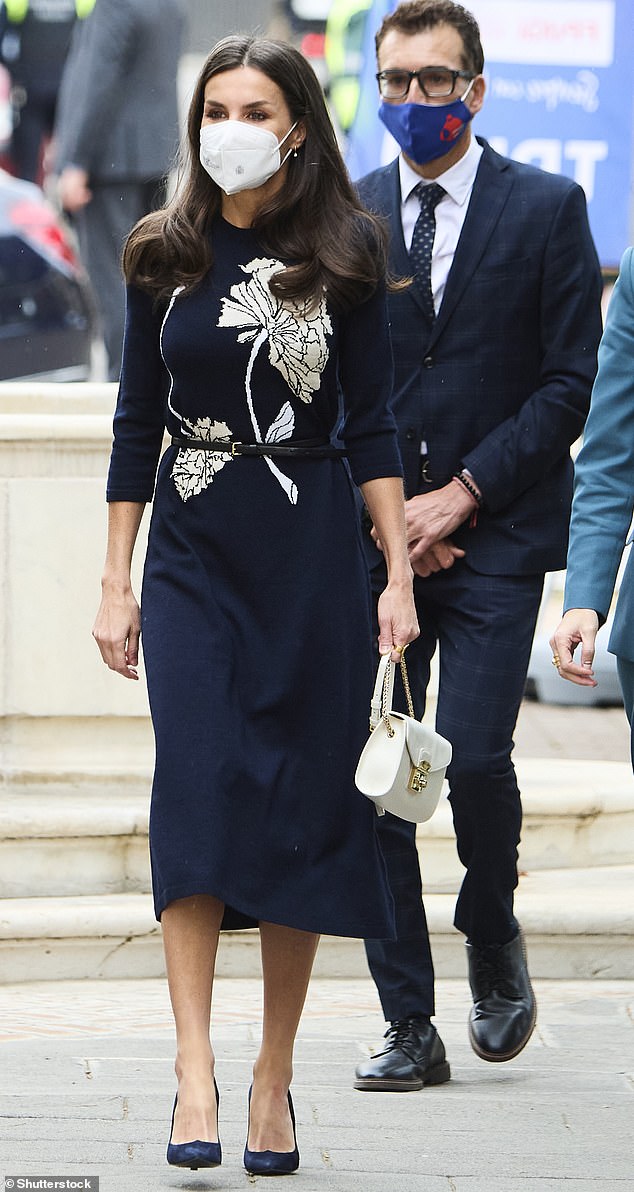 La glamorosa Reina, de 49 años, aparece en la foto con un elegante vestido midi azul marino con una rosa blanca bordada en el pecho y contempla un cinturón negro que llama la atención sobre su esbelta cintura.