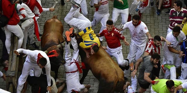 Corredores caen y son atropellados por una corrida de toros durante el encierro de las Fiestas de San Fermín en Pamplona, ​​España, el lunes 11 de julio de 2022.