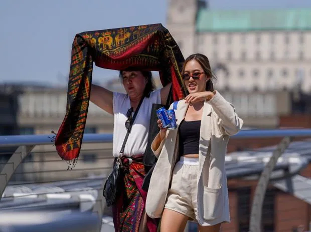 People cover themselves from the sun at Millennium Bridge during a heatwave, in London (Photo: Reuters)